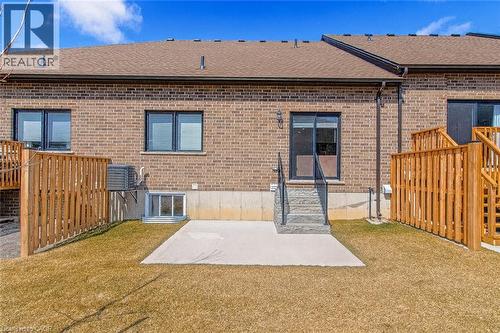 Rear view of house featuring roof with shingles, a patio area, brick siding, a lawn, and entry steps - 24 Tamarack Way, Simcoe, ON - Outdoor With Exterior