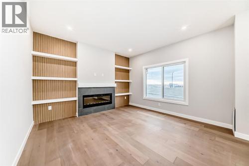 Living room with built ins and fireplace - 508 Heritage Boulevard, Cochrane, AB - Indoor Photo Showing Other Room With Fireplace