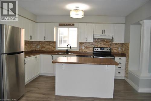 Kitchen featuring appliances with stainless steel finishes, dark countertops, white cabinets, under cabinet range hood, and backsplash - 154 Harding Street, Kitchener, ON - Indoor Photo Showing Kitchen With Double Sink