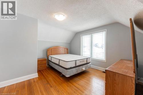 Bedroom featuring lofted ceiling, a textured ceiling, baseboards, and wood finished floors - 854 West 5Th Street, Hamilton, ON - Indoor Photo Showing Bedroom