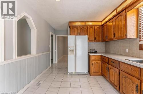 Kitchen with brown cabinetry, tasteful backsplash, white refrigerator with ice dispenser, and light countertops - 854 West 5Th Street, Hamilton, ON - Indoor Photo Showing Kitchen