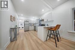 Kitchen featuring a kitchen breakfast bar, stainless steel appliances, white cabinetry, a peninsula, and light wood-type flooring - 