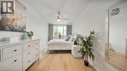 Bedroom with a textured ceiling, light wood finished floors, and ceiling fan - 