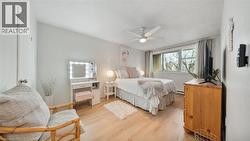 Bedroom featuring light wood-type flooring, a textured ceiling, ceiling fan, and a baseboard heating unit - 