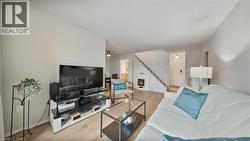 Living room featuring wood finished floors, stairway, and a lit fireplace - 