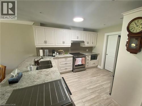 Kitchen with appliances with stainless steel finishes, white cabinetry, light stone countertops, under cabinet range hood, and a peninsula - 36 Mckenna Court, Hamilton, ON - Indoor Photo Showing Kitchen With Double Sink