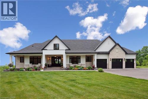 Modern farmhouse style home featuring a porch, stone siding, a front lawn, driveway, and a shingled roof - 5020 First Line, Erin, ON - Outdoor With Deck Patio Veranda With Facade
