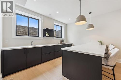Kitchen featuring a sink, a breakfast bar, dark cabinetry, a peninsula, and light countertops - 5020 First Line, Erin, ON - Indoor Photo Showing Other Room
