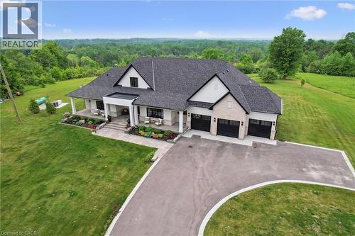 View of front of property with asphalt driveway, a wooded view, covered porch, and a garage - 5020 First Line, Erin, ON - Outdoor