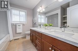 Full bathroom with double vanity, light tile patterned floors, and shower / bath combo - 