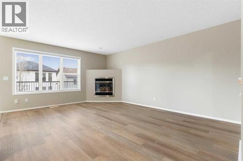 Spacious living room, corner gas fireplace, large windows, luxury vinyl plank flooring - 129 Evansbrooke Way Nw, Calgary, AB - Indoor Photo Showing Living Room With Fireplace
