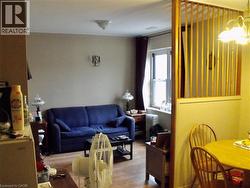 Living room with wood finished floors, radiator heating unit, and hanging lights - 