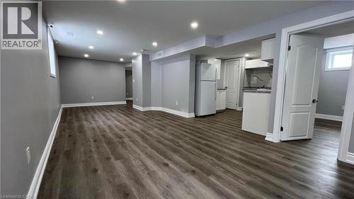 Below grade area with freestanding refrigerator, dark wood-style floors, and recessed lighting - 29 Birchcliffe Crescent Unit# 2, Hamilton, ON - Indoor