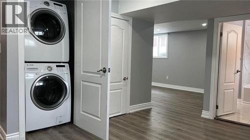 Laundry area with stacked washing machine and dryer and dark wood-style floors - 29 Birchcliffe Crescent Unit# 2, Hamilton, ON - Indoor Photo Showing Laundry Room
