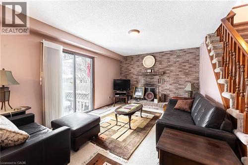 Living area with a textured ceiling, brick wall, and a fireplace - 5 Charing Drive, Hamilton, ON - Indoor Photo Showing Living Room With Fireplace