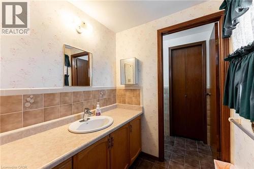 Full bathroom featuring wallpapered walls, vanity, and dark tile patterned floors - 5 Charing Drive, Hamilton, ON - Indoor Photo Showing Bathroom