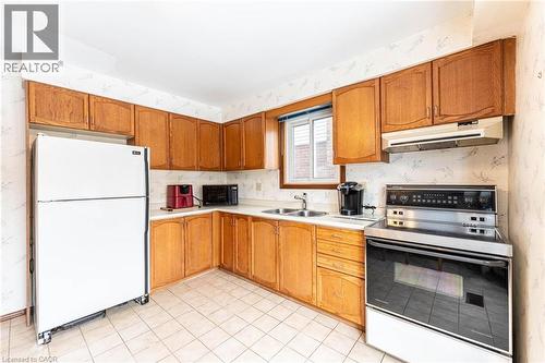 Kitchen featuring electric range oven, freestanding refrigerator, wallpapered walls, light countertops, and wood finish cabinetry - 5 Charing Drive, Hamilton, ON - Indoor Photo Showing Kitchen With Double Sink