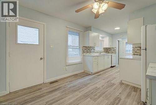Kitchen with light countertops, white cabinetry, ceiling fan, light wood finished floors, and white appliances - 310 Magnolia Drive, Hamilton, ON 
