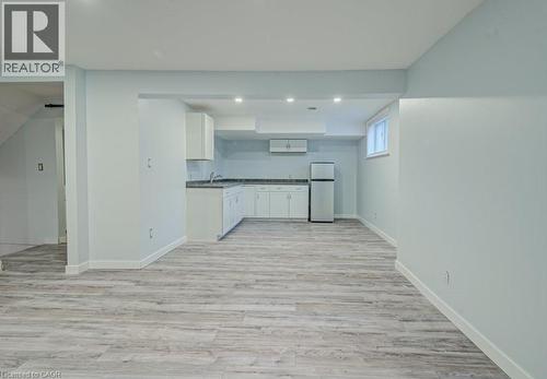Kitchen with white cabinets, freestanding refrigerator, light wood-type flooring, recessed lighting, and dark countertops - 310 Magnolia Drive, Hamilton, ON 