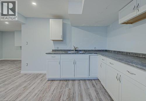 Kitchen with light wood-type flooring, white cabinets, dark countertops, and recessed lighting - 310 Magnolia Drive, Hamilton, ON 