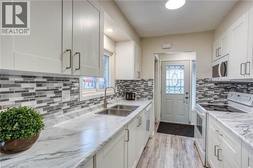 Kitchen featuring white appliances, white cabinetry, light wood-type flooring, and light stone counters - 310 Magnolia Drive, Hamilton, ON - Indoor Photo Showing Kitchen With Double Sink With Upgraded Kitchen