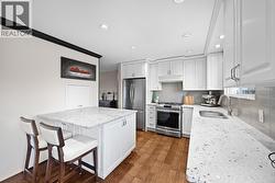 Updated and functional kitchen with ample cabinetry, generous counter space, stainless steel appliances, and a central island with seating. Designed for both everyday use and entertaining. - 