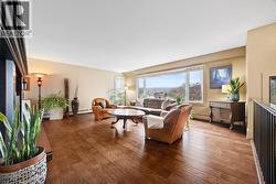 Bright and comfortable living room featuring large windows that bring in plenty of natural light, hardwood flooring, and a cozy gas fireplace. An ideal space for everyday living or entertaining. - 
