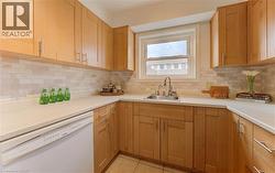 Kitchen with white dishwasher, light countertops, light tile patterned floors, and backsplash - 