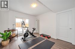 Exercise room featuring light wood-style flooring and baseboards - 