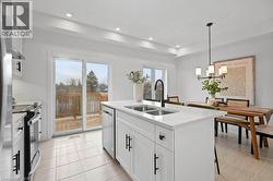Kitchen featuring stainless steel appliances, white cabinets, hanging light fixtures, a kitchen island with sink, and recessed lighting - 