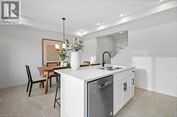 Kitchen with a kitchen bar, dishwasher, hanging light fixtures, an island with sink, and white cabinetry - 