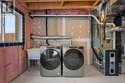 Washroom with washer and clothes dryer, concrete flooring, and heating unit - 