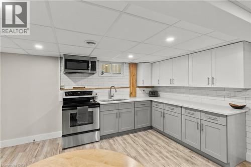 Kitchen featuring gray cabinets, stainless steel appliances, light wood finished floors, backsplash, and a drop ceiling - 40 Bula Drive, St. Catharines, ON - Indoor Photo Showing Kitchen