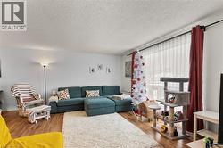 Living area with a textured ceiling and light wood-type flooring - 