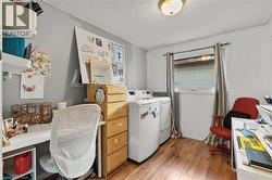 Office featuring a textured ceiling, light wood-style flooring, and washing machine and clothes dryer - 