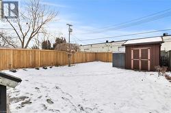 Yard layered in snow featuring a fenced backyard and a storage unit - 