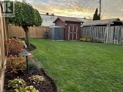 Fenced backyard featuring a storage unit - 