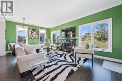 Living room with crown molding, healthy amount of natural light, a premium fireplace, and dark wood finished floors - 