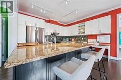 Kitchen with white cabinets, crown molding, stainless steel fridge, open shelves, and dark wood-style floors - 