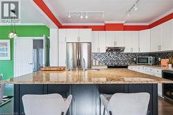 Kitchen featuring crown molding, light stone countertops, white cabinetry, and stainless steel appliances - 