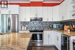 Kitchen featuring open shelves, appliances with stainless steel finishes, crown molding, wine cooler, and white cabinetry - 