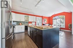 Kitchen with open shelves, stainless steel appliances, white cabinets, tasteful backsplash, and decorative light fixtures - 