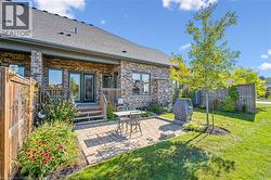 Rear view of house featuring a patio, brick siding, and a shingled roof - 