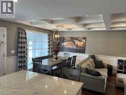 Dining area with a decorative wall, wainscoting, a chandelier, coffered ceiling, and dark wood-type flooring - 