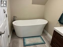 Full bathroom with vanity, a freestanding bath, and light wood-style flooring - 