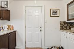 Kitchen with dark wood finish cabinets, backsplash, light stone counters, and glass fronted cabinets - 