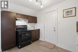 Kitchen with electric range, dark wood finish cabinetry, lofted ceiling, and light wood finished floors - 