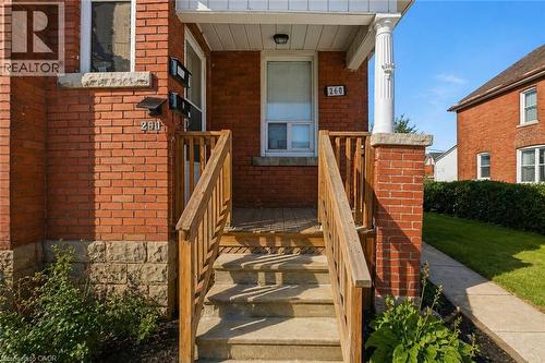 Brick exterior with concrete steps and wood railings leading to a covered porch entry - 260 Prospect Street S, Hamilton, ON - Outdoor With Exterior