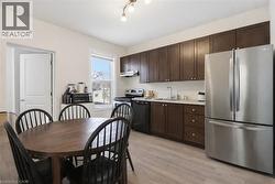 Kitchen featuring stainless steel appliances, light countertops, dark wood finish cabinetry, and light wood-style floors - 