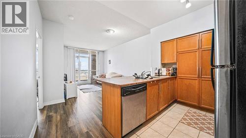 Kitchen featuring brown cabinets, a peninsula, appliances with stainless steel finishes, light countertops, and open floor plan - 388 Prince Of Wales Drive Unit# 1609, Mississauga, ON - Indoor Photo Showing Kitchen With Double Sink